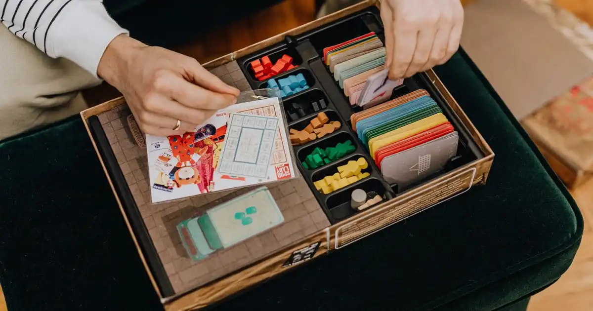 Long boxes of trading cards beside a phone cataloging a collection