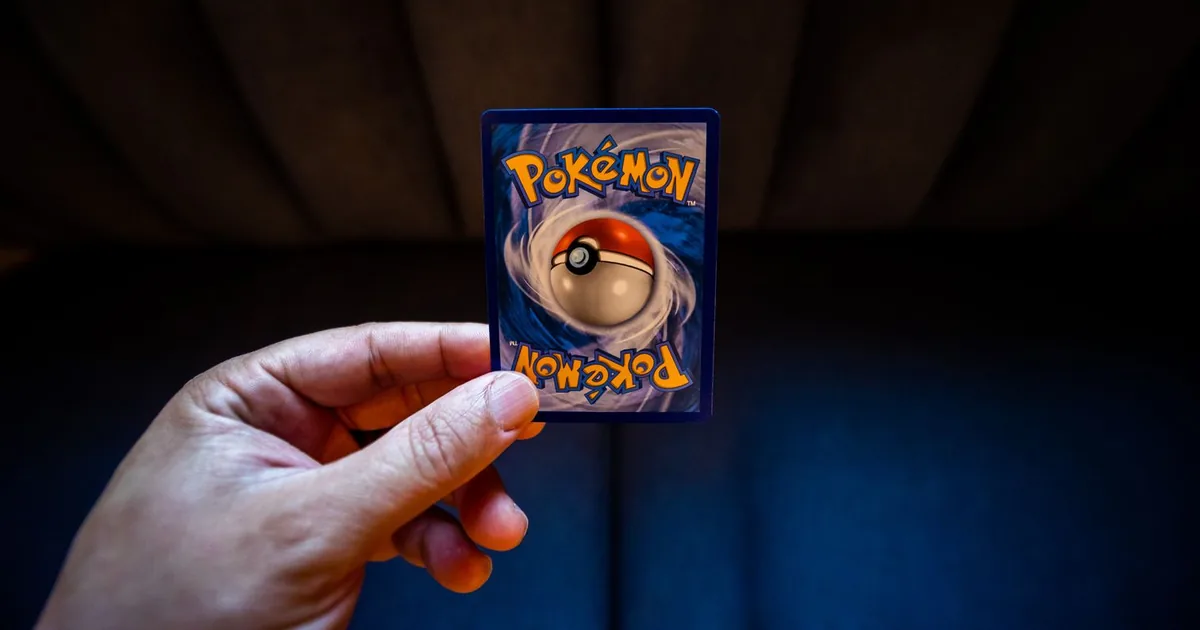 Person holding a colorful trading card against a dark background