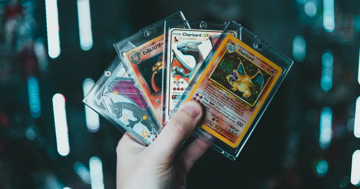 Hand holding Charizard cards with a soft bokeh background